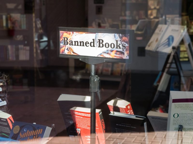 A sign reading "banned books" in a bookshop window display