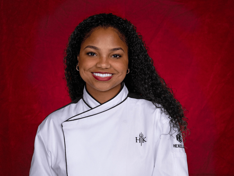 Promotional portrait of Hell's Kitchen Season 24 contestant Jada Vidal, wearing a chef coat and smiling.