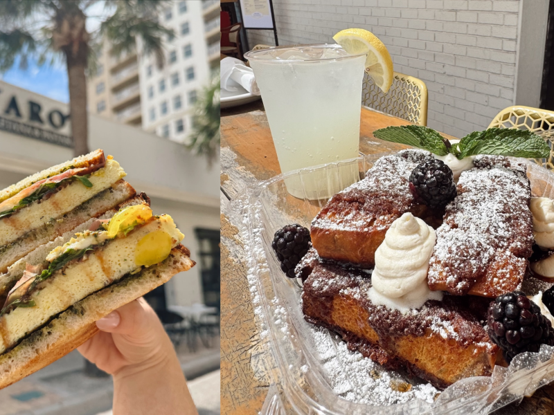 A split image featuring two food shots. On the left, a hand holds a toasted sandwich layered with egg, pesto, and tomatoes, set against a blurred background of a building with a "BAVARO" sign and palm trees. On the right, a clear plastic container sits on an outdoor wooden table, filled with thick French toast topped with powdered sugar, blackberries, whipped cream, and mint, accompanied by a cold drink garnished with a lemon wedge.
